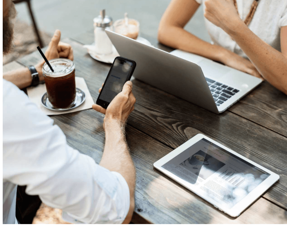 Business meeting with laptop, tablet, and phone on a wooden table